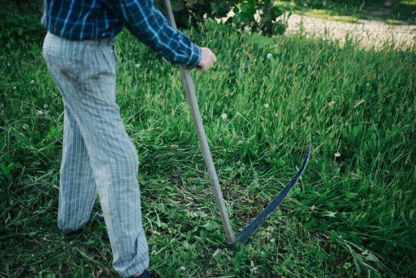 using a scythe to mow under a trampoline